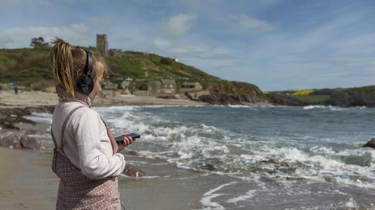 A child wearing headphones stares out to see while listening to audio.